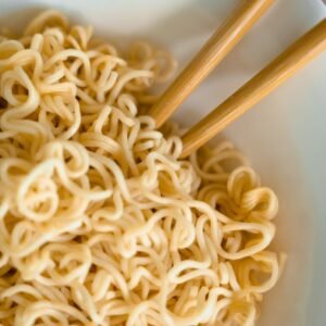 Tasty close-up of cooked noodles in a bowl with chopsticks for an Asian dining experience.